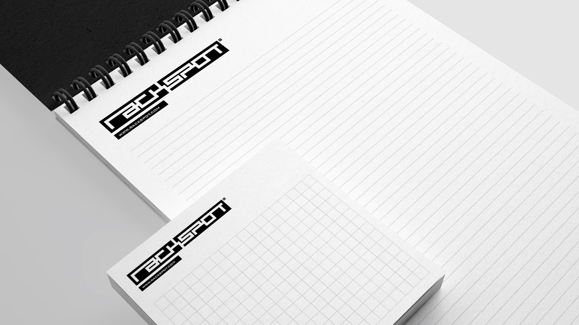 Spiral notebook and grid notepad featuring the "Rackspot" logo on black and white background.