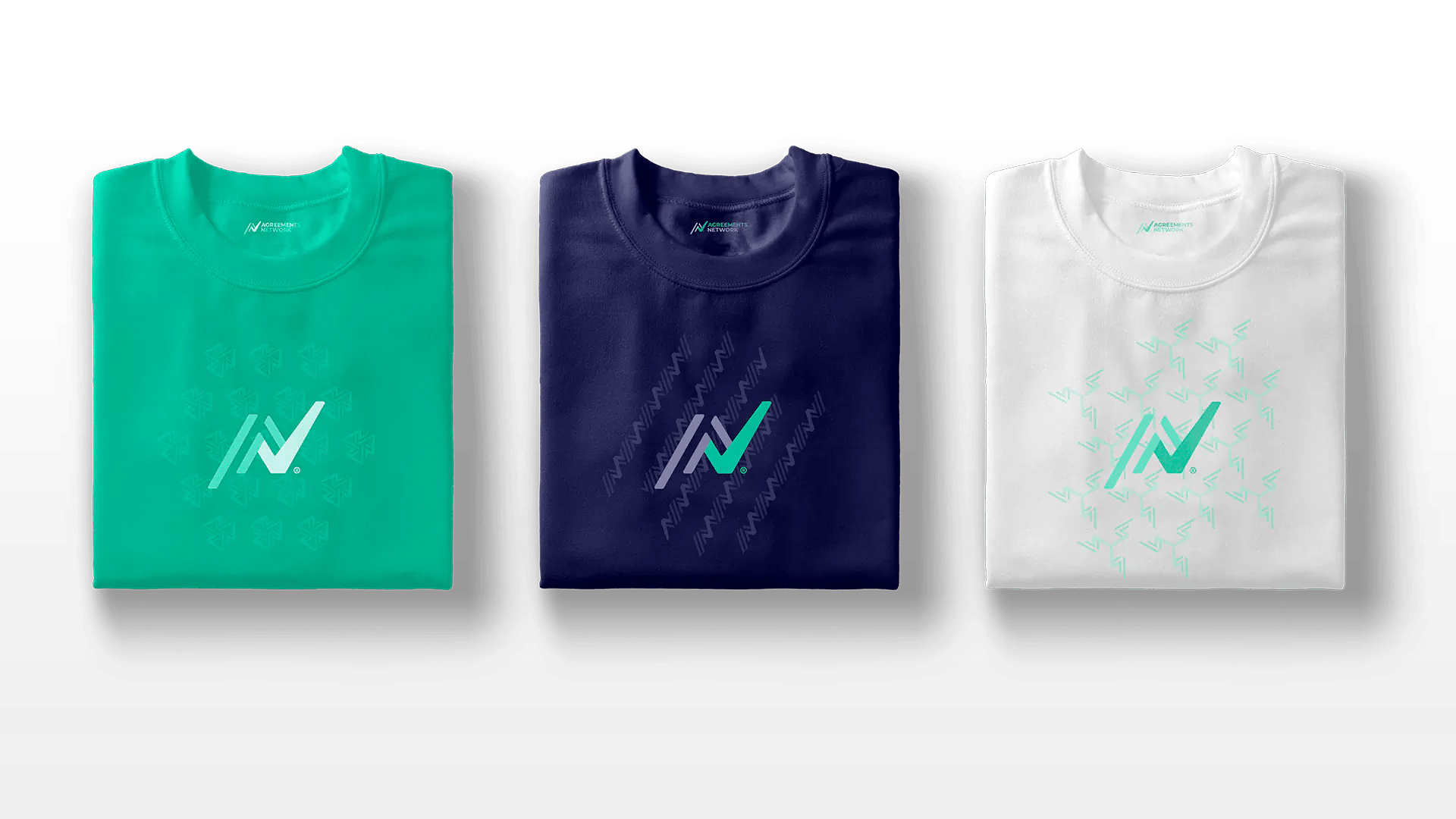 Three folded t-shirts in teal, navy, and white, each with a matching "AN" logo on the front.